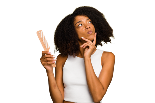 Young african american woman holding hair comb isolated looking sideways with doubtful and skeptical expression.