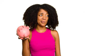 Young African American woman holding a piggy bank isolated confused, feels doubtful and unsure.
