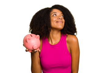 Young African American woman holding a piggy bank isolated dreaming of achieving goals and purposes