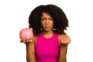 Young African American woman holding a piggy bank isolated showing fist to camera, aggressive facial expression.
