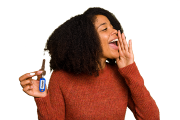 Young African american woman holding home keys isolated shouting and holding palm near opened mouth.