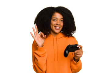Young African American woman holding a game controller isolated cheerful and confident showing ok gesture.