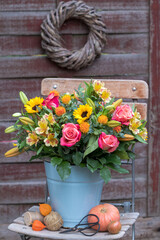 Blumenstrauß mit pink Rosen, Sonnenblumen, Lilien und Färberdisteln im vintage Eimer