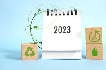 Year 2023 business sustainability goal and sustainable development target concept. Desk calendar with ecological environment icons and green plant.