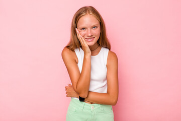 Caucasian teen girl isolated on pink background laughs happily and has fun keeping hands on stomach.