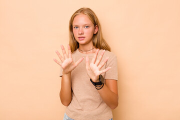 Caucasian teen girl isolated on beige background rejecting someone showing a gesture of disgust.