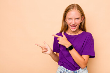 Caucasian teen girl isolated on beige background pointing with forefingers to a copy space, expressing excitement and desire.