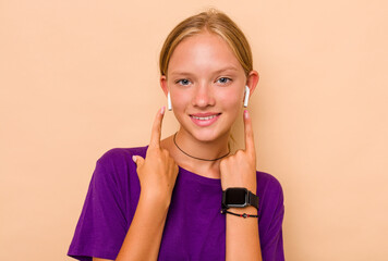 Little caucasian girl listening music isolated on beige background