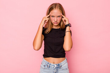 Caucasian teen girl isolated on pink background focused on a task, keeping forefingers pointing head.