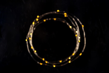 Fairy lights, blurred led garland, shot from above on a black background. Abstract festive frame