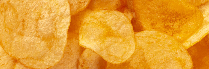 Potato chips texture, a salty snack panorama, a pile of yellow crisps, overhead panoramic banner