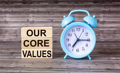 Conceptual words Our Core Values on wooden blocks on wooden background with clock. Business value and our concept of core values. Copy space.