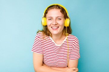 Young caucasian woman wearing headphones isolated on blue background laughing and having fun.
