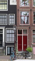 Fototapeta na wymiar Amsterdam Traditional House Facades Close Up with Red Door, Vintage Lamp Post and Bicycles, Netherlands
