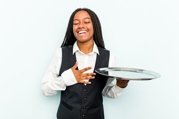 Young African American waitress woman holding a tray isolated on blue background laughs out loudly...