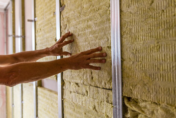 Worker insulating a room wall with mineral rock wool thermal insulation. - obrazy, fototapety, plakaty
