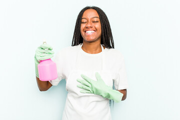 Young African American cleaner woman isolated on blue background laughs out loudly keeping hand on chest.