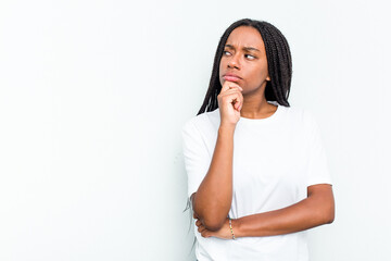 Young African American woman isolated on white background looking sideways with doubtful and skeptical expression.