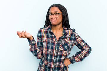 Young African American woman with braids hair isolated on blue background doubting and shrugging shoulders in questioning gesture.