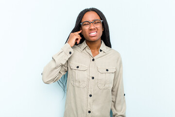 Young African American woman with braids hair isolated on blue background covering ears with fingers, stressed and desperate by a loudly ambient.