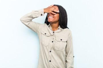 Young African American woman with braids hair isolated on blue background laughs joyfully keeping hands on head. Happiness concept.