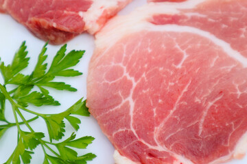 Raw Pork Slice in White Round Plate decorated with parsley. Fresh raw pork.
