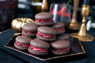 Brown chocolate macaroons with pink filling. Cream forest berries