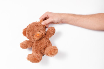 male hand holding a toy bear on a white