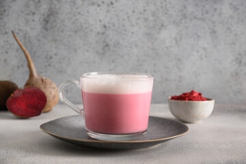 Beetroot latte or pink moon milk latte in glass cup of beetroot powder and vegan milk on gray background. Great warming drink. Close up.