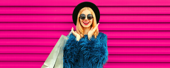 Portrait of beautiful stylish smiling woman with shopping bags wearing blue fur coat, black round...