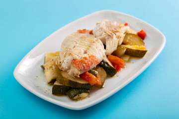 Fried fish with baked vegetables on white dish