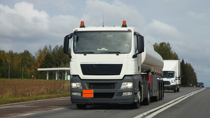 Fototapeta na wymiar White semi truck fuel tanker drive on suburban highway road at autumn day, front view, ADR cargo transportation logistics in Europe