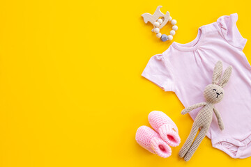 Newborn baby bodysuit with rabbit toy, flat lay, top view