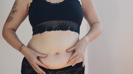 Tattooed woman in black underwear with fat belly, overweight female body isolated on white background. Lose weight. concept of surgery, subcutaneous fat breakdown.