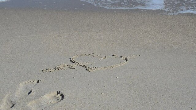 Heart on sand. Heart on sand, is washed away by a wave