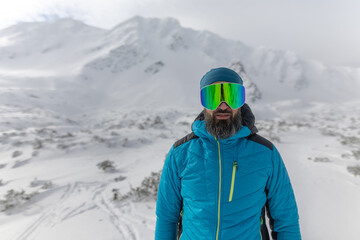 Fototapeta na wymiar Man with ski glasses, preparing for winter skiing in snowy mountains.