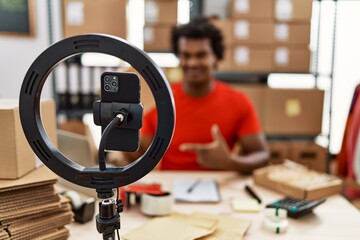 African man working at small business ecommerce doing video tutorial looking positive and happy standing and smiling with a confident smile showing teeth