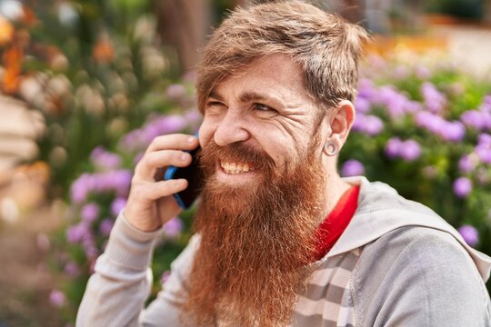 Young redhead man smiling confident talking on the smartphone at park