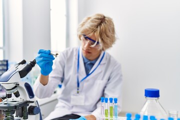 Young blond man scientist holding sample with tweezer at laboratory