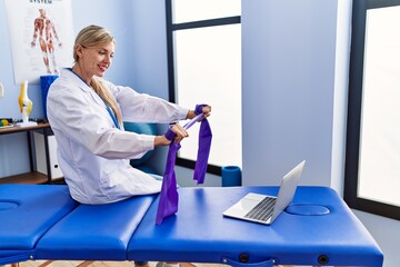 Young blonde woman wearing physiotherpist having online recovery session at physiotherapy clinic