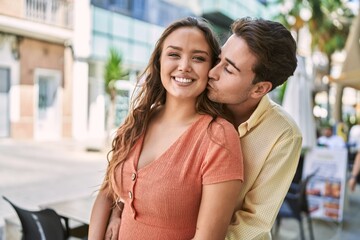Obraz premium Man and woman couple hugging and kissing at street