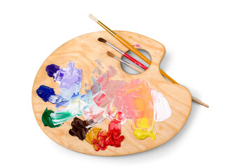 Wooden art palette with blobs of paint and a brushes on white background