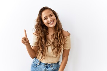 Beautiful hispanic woman standing over isolated while background showing and pointing up with...