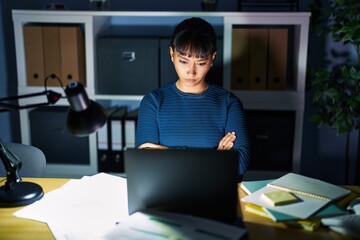 Young beautiful woman working at the office at night skeptic and nervous, disapproving expression on face with crossed arms. negative person.