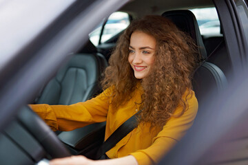 Young woman driving a car in the city. Portrait of a beautiful woman in a car, looking out of the...