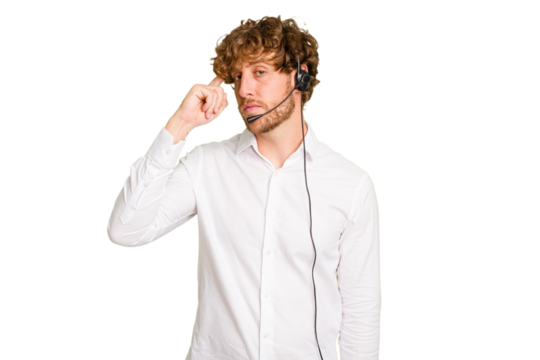 Telemarketer man working with a headset isolated on green chroma background pointing temple with finger, thinking, focused on a task.