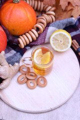 Hot cup of tea with autumn leaves, pumpkins, ginger, lemon and bagels. Autumn mood. Warming drink in cold weather, top view