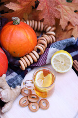 Hot cup of tea with autumn leaves, pumpkins, ginger, lemon and bagels. Autumn mood. Warming drink in cold weather, top view