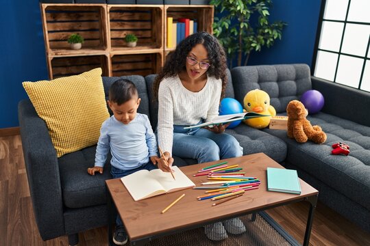 Mother and son sitting on sofa drawing at home