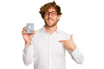 Young caucasian informatic man holding a hard drive isolated on white background person pointing by hand to a shirt copy space, proud and confident